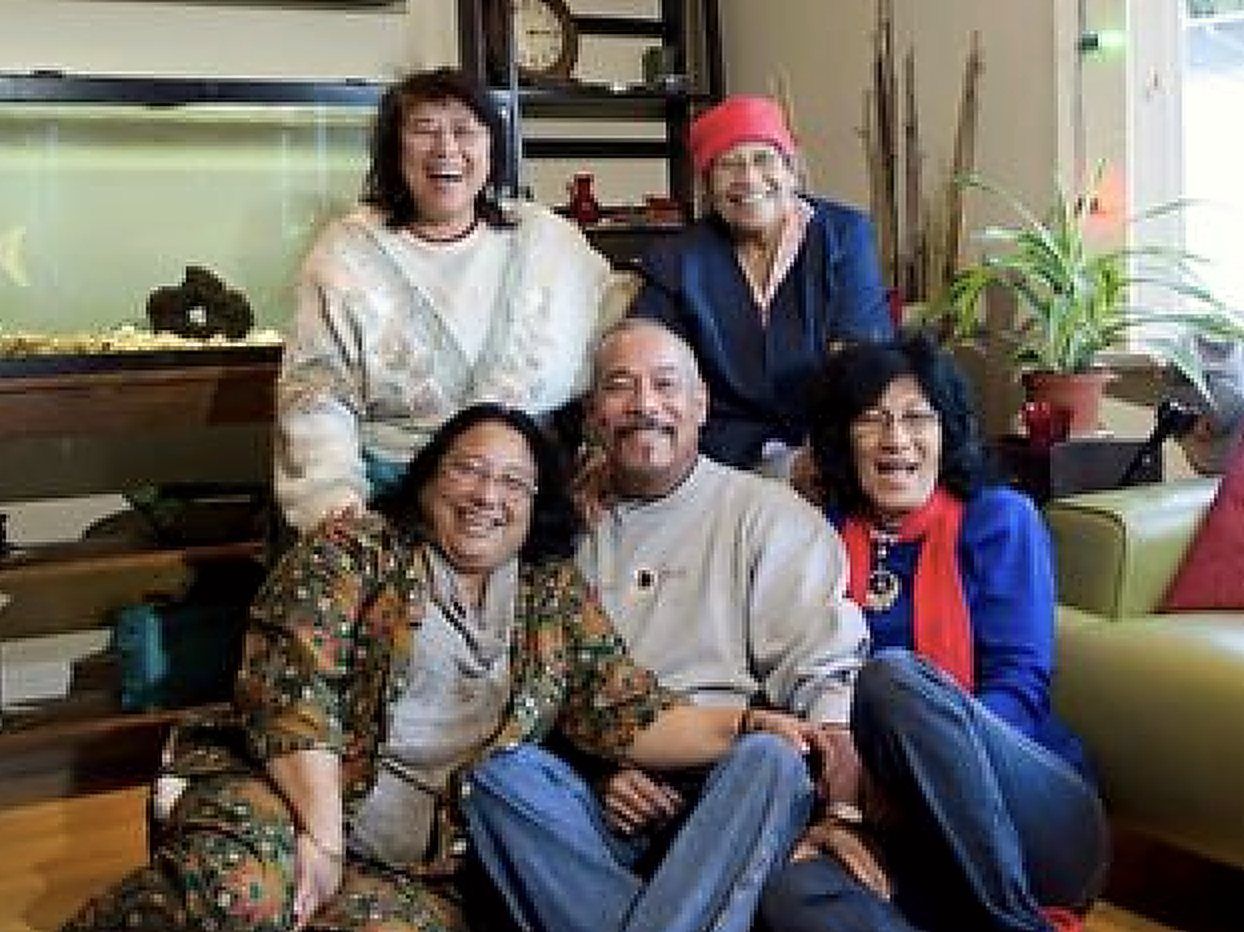 Five members of a family together in a living room, laughing